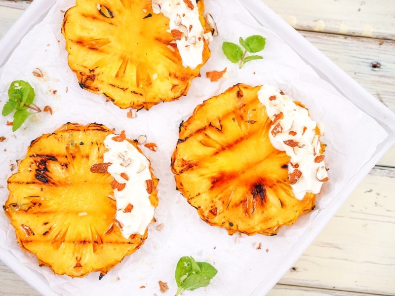 Gegrillte Ananas mit Sahne auf Porzellanteller